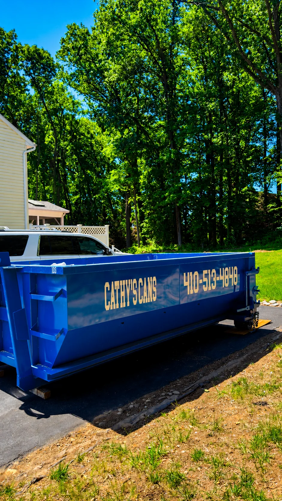 Blue 10-yard dumpster on residential driveway with white house and tree backdrop
