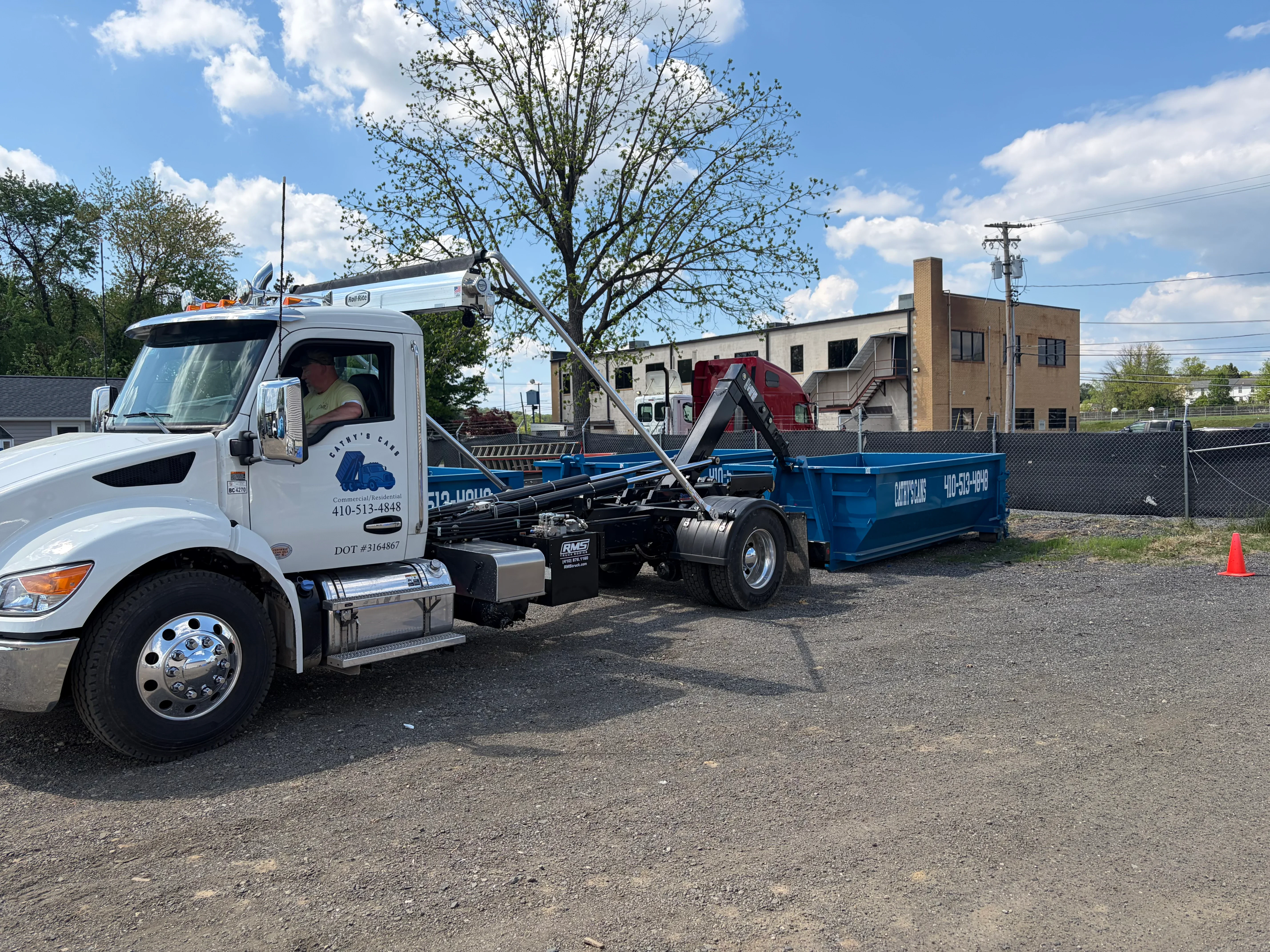 White hook truck with hydraulic lift system and blue 15-yard dumpster container
