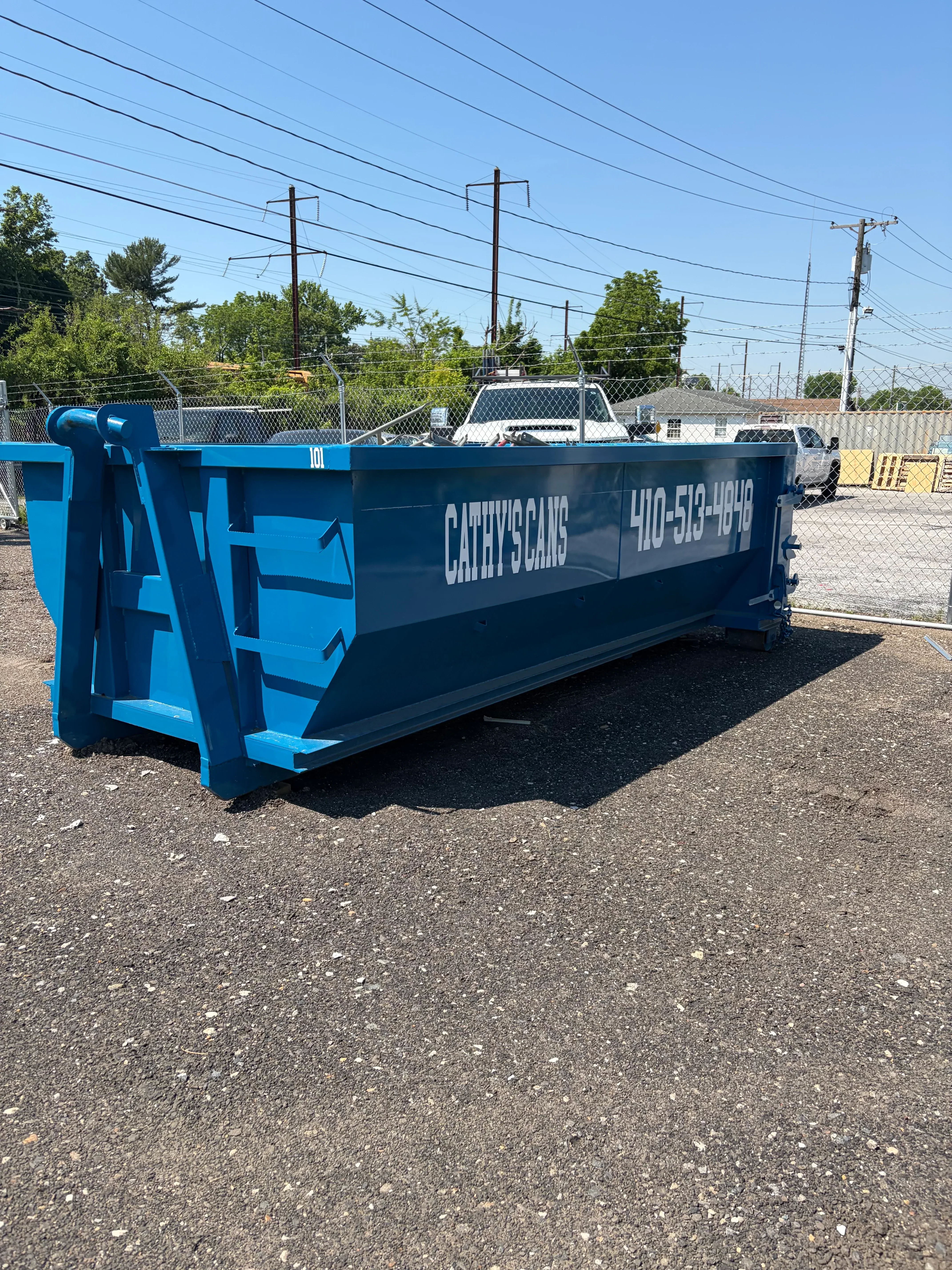 Blue and black commercial dumpster with metal construction installed on concrete pad