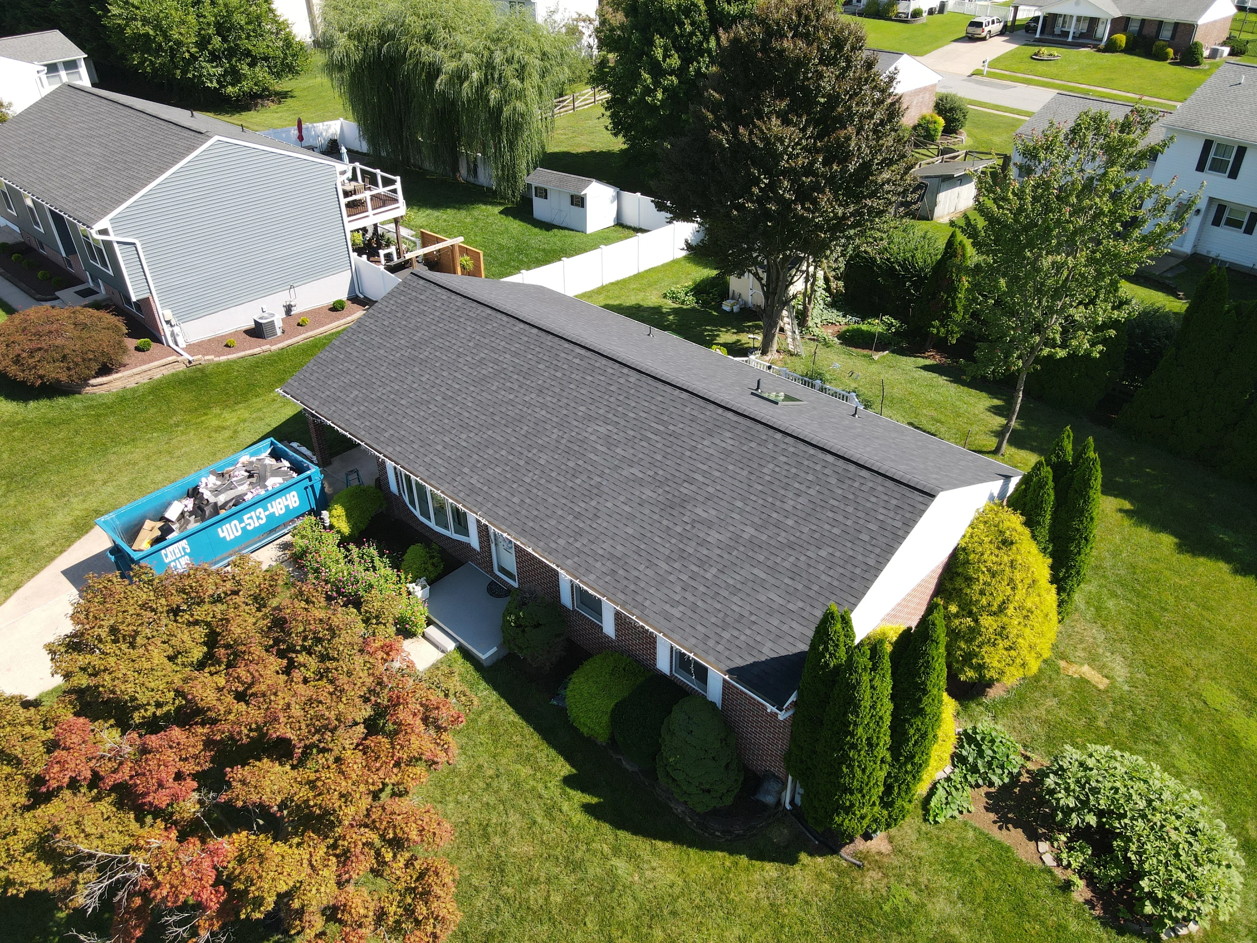 30-yard dumpster at brick home during roof replacement with new asphalt shingles