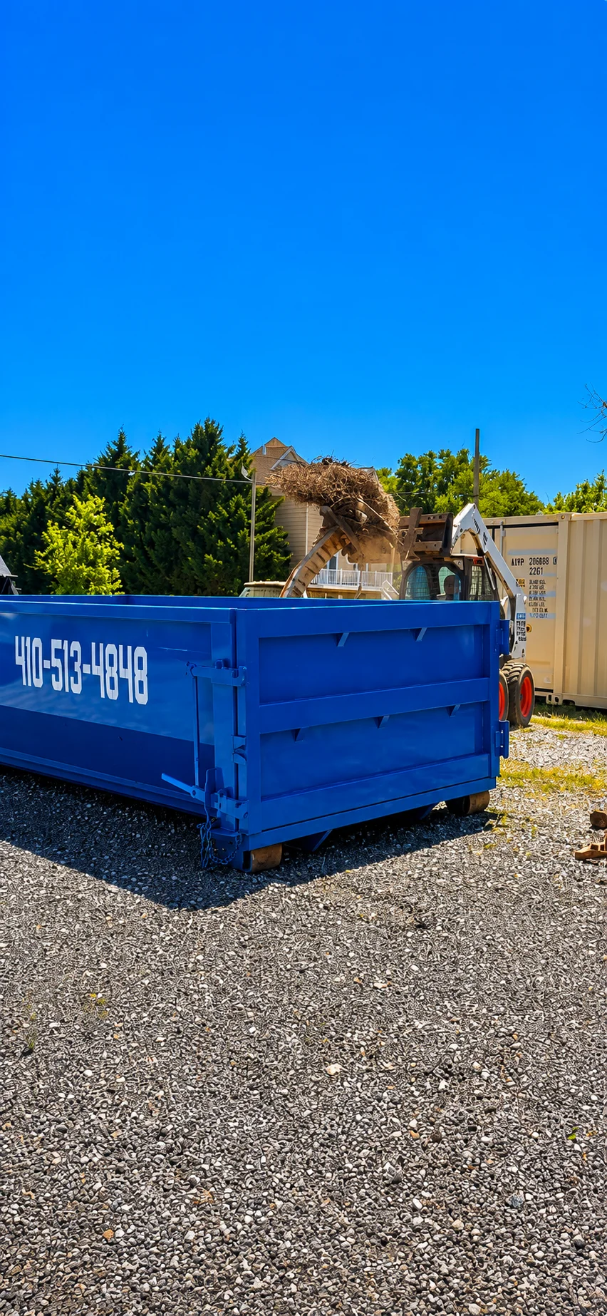 Blue roll-off dumpster loaded with construction debris, wood, and branches during residential cleanup
